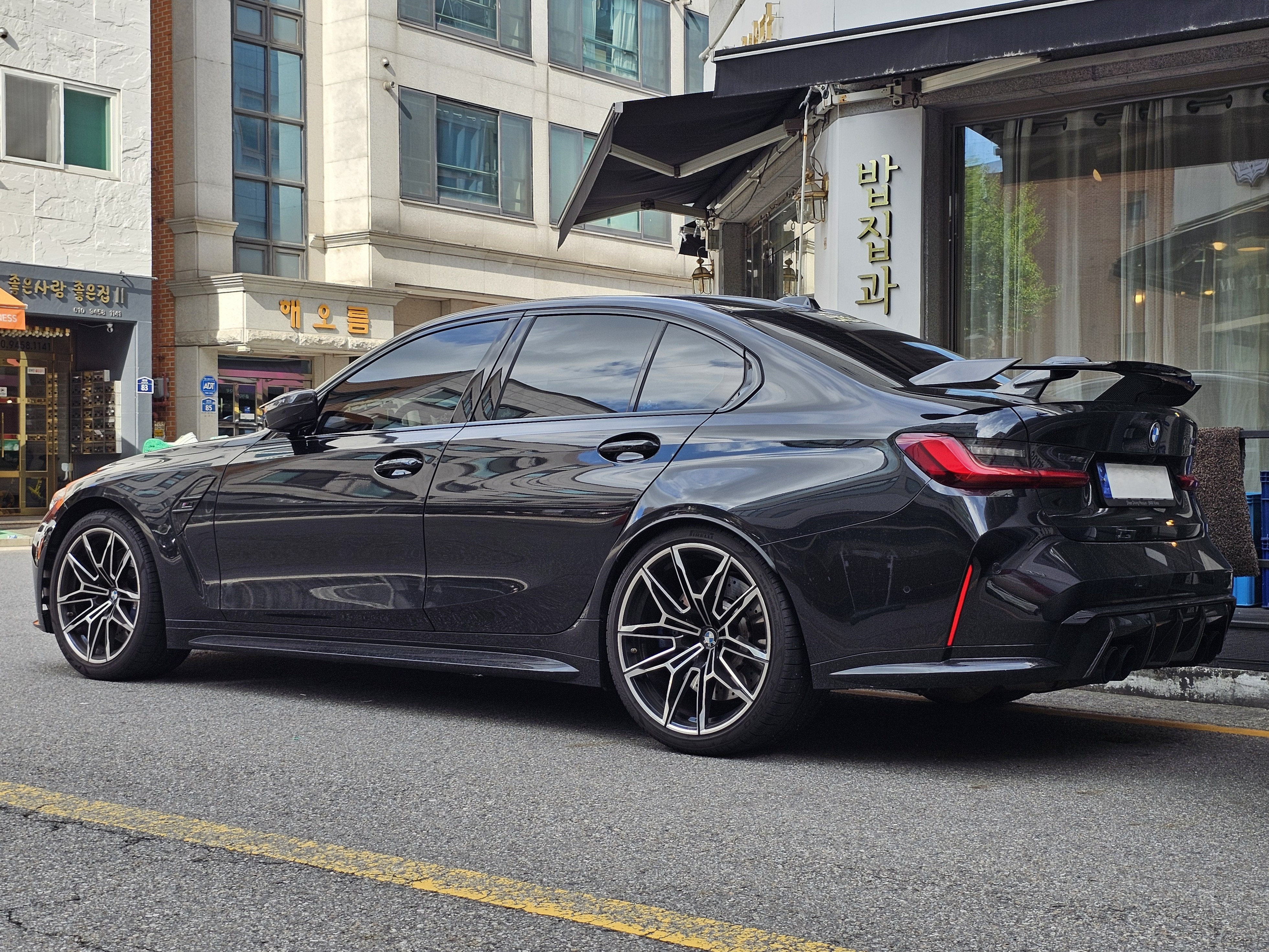 Black BMW M3 Competition, rear three-quarter view
